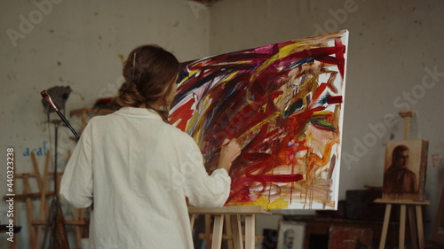 Talented woman creating at workplace. Painter using bright colors indoors.