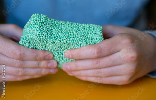 Children's hands play with a foam putty of green color