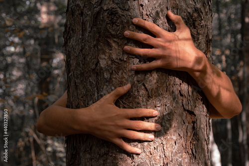 A male activist hugs a tree showing unity with nature. Social protection of forests from deforestation. Global problems.