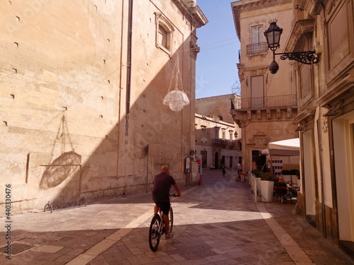 Lecci, Italy. Sunrise in old town. Play of light and shadow. Sityscape with bicycling man.