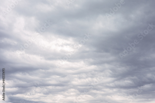 White and grey cumulus storm clouds floating in moody sky with sunlight. Natural cloudscape, fluffy cloudy scene of outdoor environment in rainy season. Abstract nature background. Mood of weather.