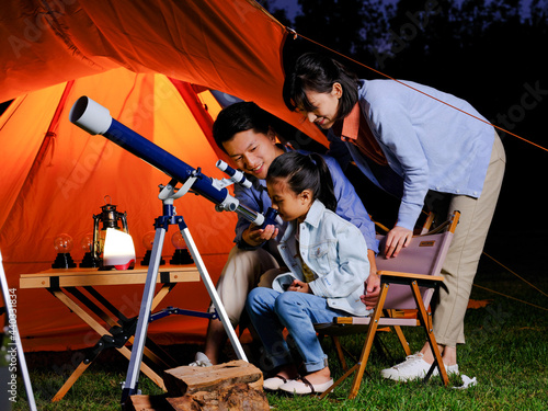 A happy family of three using telescopes outdoors