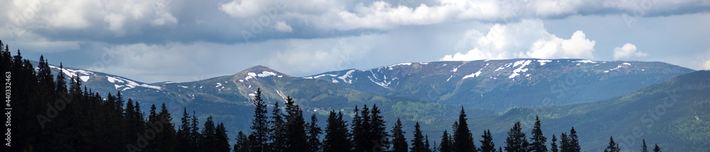 Beautiful panorama of the mountains in the summer in the snow and haze