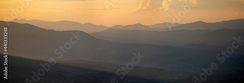 Bild auf Leinwand Silhouettes of the Carpathian mountains in the haze at sunset