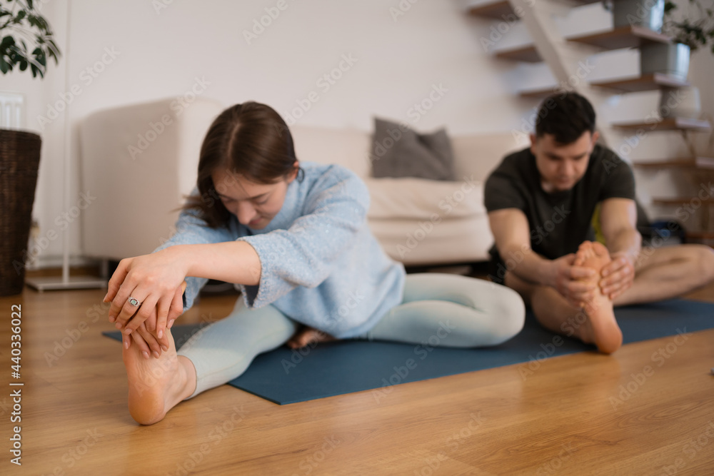 Sporty millennial couple stretching after training on mats on floor together. Spouses relaxing after workout at home Sporty millennial couple stretching after training on mats on floor together. Spouses relaxing after workout at home