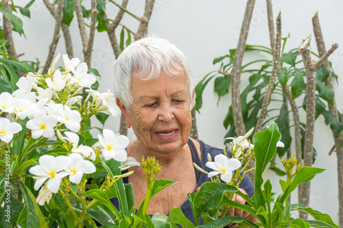 Mulher idosa cuidando do jardim florido