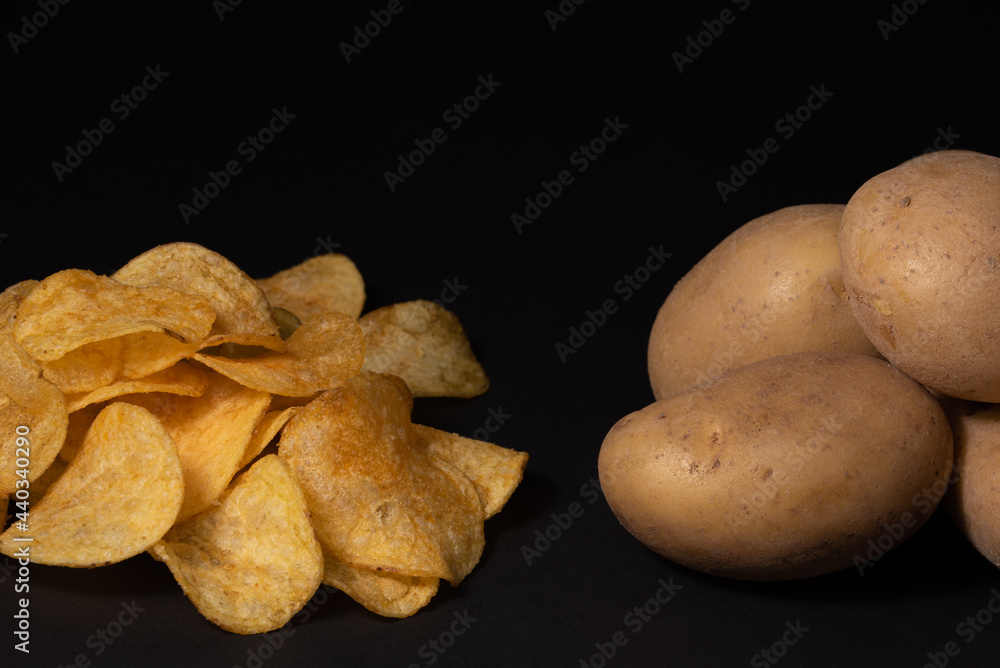 Chips and potato tubers on a black background.