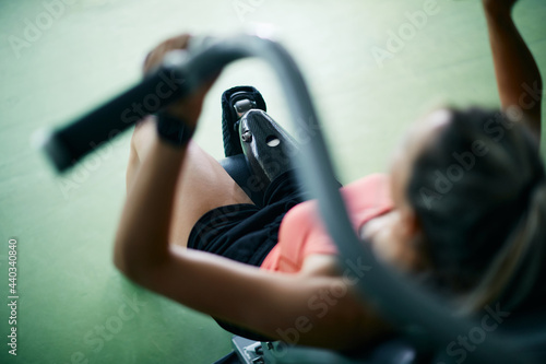 Close-up of sportswoman with artificial leg uses exercise machine while working out in a gym. photo