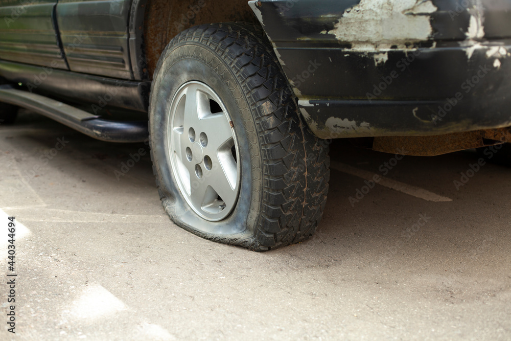 A deflated car wheel. Punctured tire on the car. Damaged transport. A deflated car wheel. Punctured tire on the car. Damaged transport.