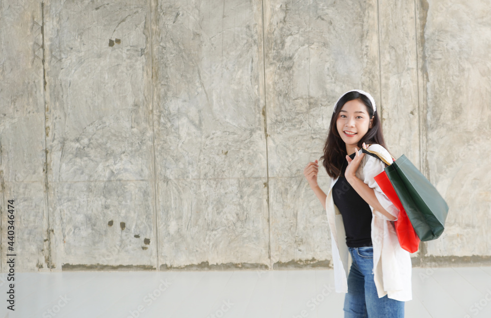 A woman carrying a shopping bag in a cheerful Asian mall is having fun shopping: She happily carries a shopping bag with the latest offers at the shopping center.