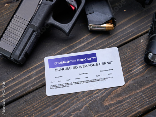 Concealed Carry Permit sitting on a table next to semi-automatic handgun pistol with spare magazine clip