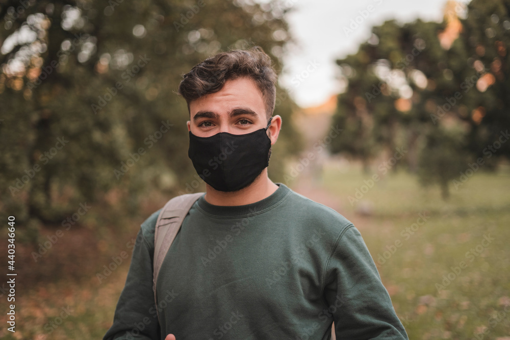 Portrait of a young handsome Caucasian man with mask in a park Portrait of a young handsome Caucasian man with mask in a park