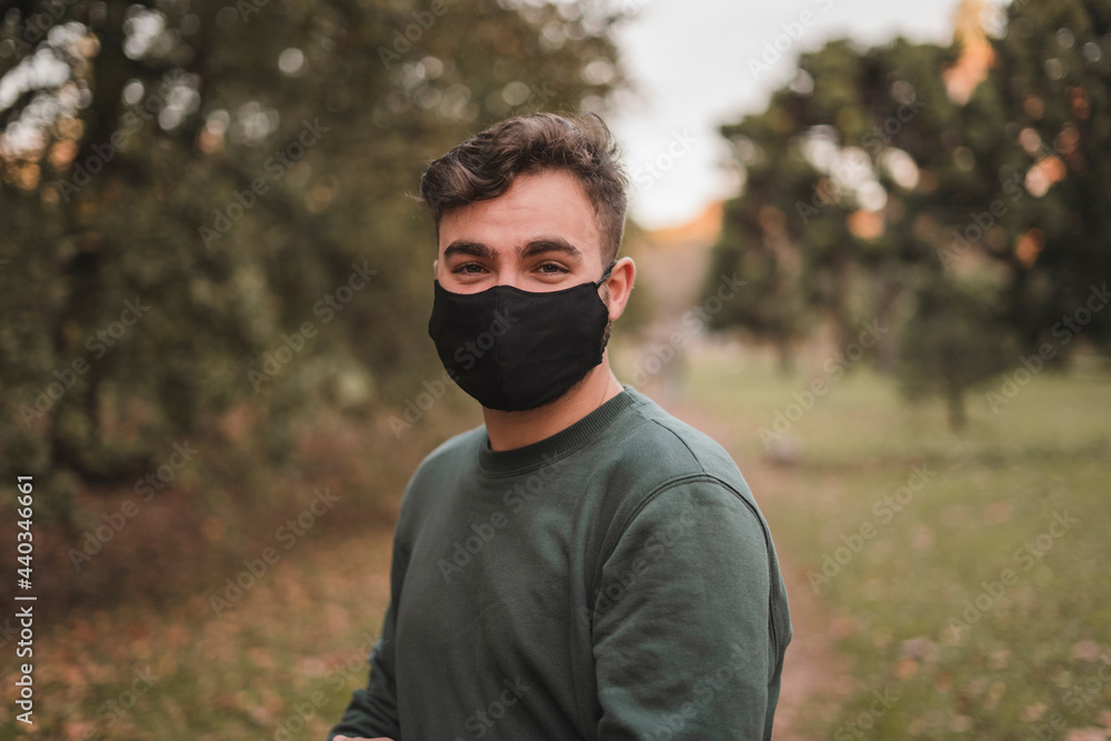 Portrait of a young handsome Caucasian man with mask in a park Portrait of a young handsome Caucasian man with mask in a park