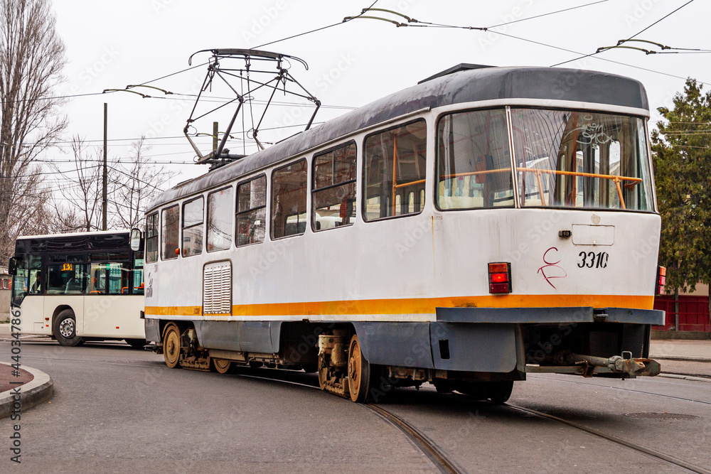 Old electric tram driving through the streets of downtown Bucharest on cloudy day