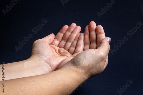 Two white woman's hands together with the palm facing up on a dark background. Mention of request for help, need for peace and requests in a general context.