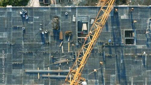 Aerial top down view on the rooftop of an apartment building under construction with tower crane and a lot of workers laying metal rebar photo
