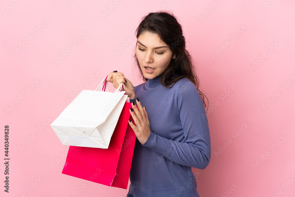 Teenager Russian girl isolated on pink background holding shopping bags Teenager Russian girl isolated on pink background holding shopping bags