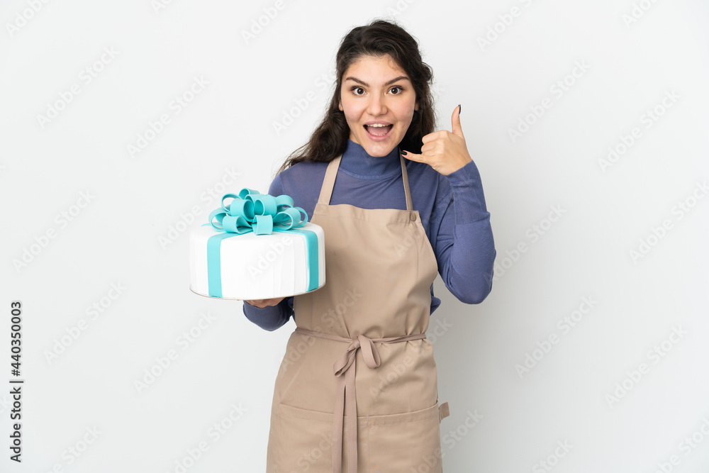 Pastry Russian chef holding a big cake isolated on white background making phone gesture. Call me back sign Pastry Russian chef holding a big cake isolated on white background making phone gesture. Call me back sign