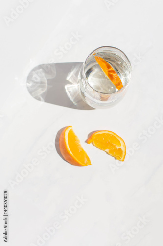 Still life orange slices and iridescent glass on white marble background