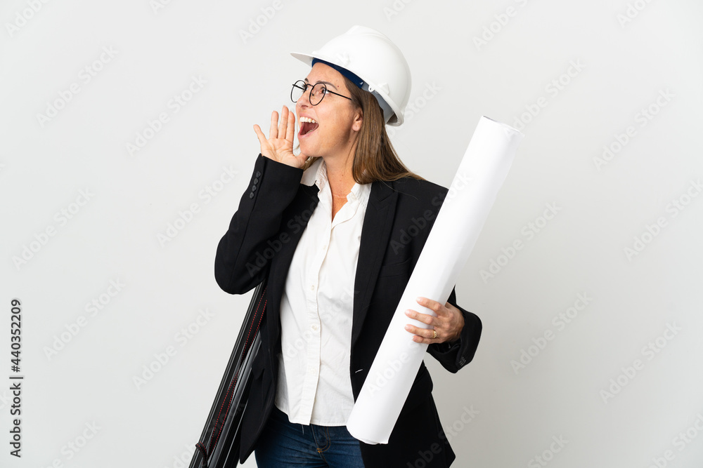 Middle age architect woman with helmet and holding blueprints over isolated background shouting with mouth wide open to the side Middle age architect woman with helmet and holding blueprints over isolated background shouting with mouth wide open to the side
