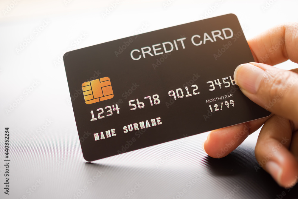 Hand holding credit card on gray background. technology electronic for payment purchase shopping online black fridays. finance lifestyle and business concept. Hand holding credit card on gray background. technology electronic for payment purchase shopping online black fridays. finance lifestyle and business concept.