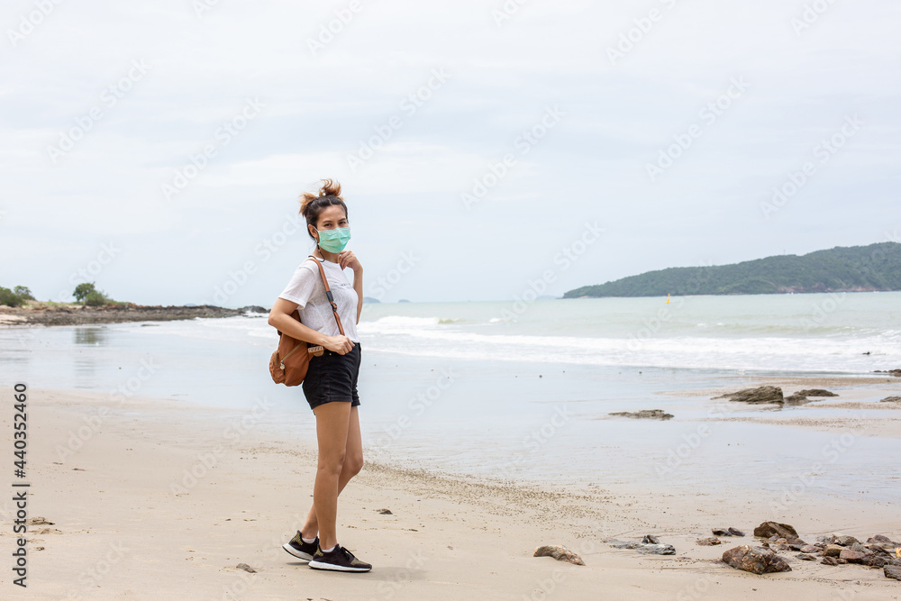 A woman wearing a mask walks on the beach and sea during the coronavirus pandemic. A woman wearing a mask walks on the beach and sea during the coronavirus pandemic.