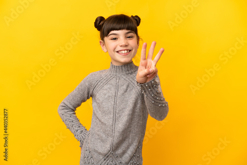 Fototapet Little caucasian girl isolated on yellow background happy and counting three wit