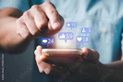 a man using smart phone typing to communicate with others through emoji and text online. concept with notification icons of like, message, email, comment and star above smartphone screen