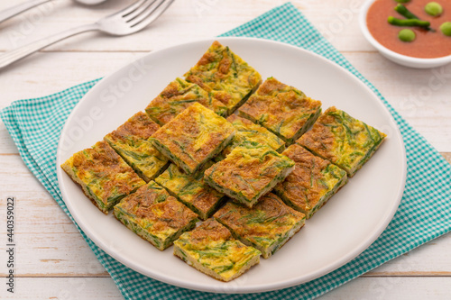 Climbing wattle omelet or cha om egg, a simple-healthy Thai dish, served with spicy shrimp paste dip or nam prik kapi. It is a good omelet stuffed with vegetable to pair with plain cooked rice. photo