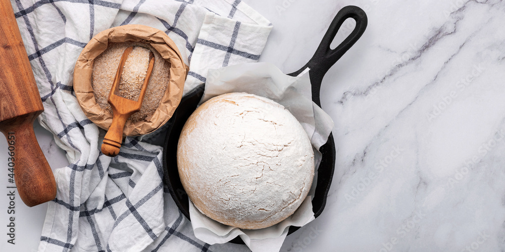 Fresh raw homemade yeast dough resting in cast iron skillet on marble table flat lay. Fresh raw homemade yeast dough resting in cast iron skillet on marble table flat lay.