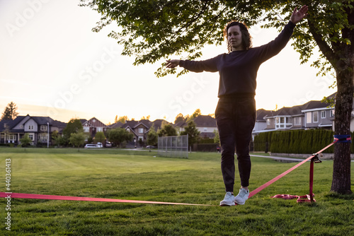 Принти на полотні Adventurous White Caucasian Adult Woman walking on a Slackline between trees in a neighborhood park