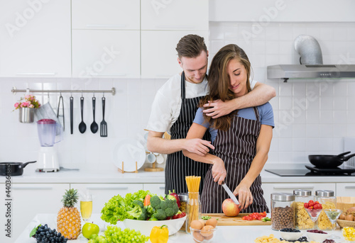 Romantic young couple at kitchen. Woman cutting fresh organic apple. Healthy Dieting Food Concept. .