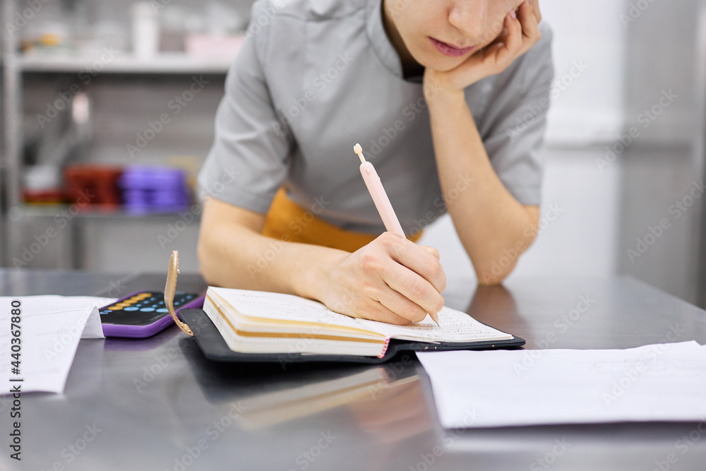 The pastry chef girl makes notes in a notebook. The pastry chef girl makes notes in a notebook.