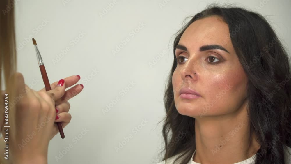 Professional makeup artist applies eye shadow to a young woman. Professional makeup artist applies eye shadow to a young woman.