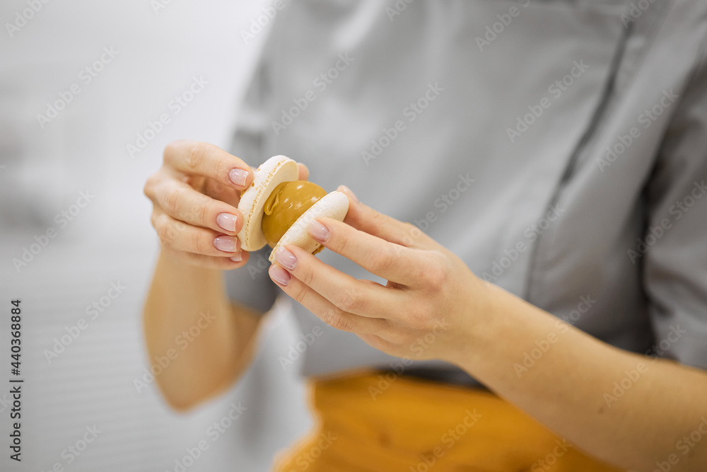 A bright girl holds fresh cakes and macaroons in her hands A bright girl holds fresh cakes and macaroons in her hands