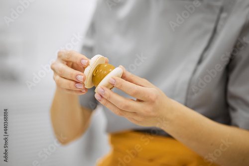 A bright girl holds fresh cakes and macaroons in her hands