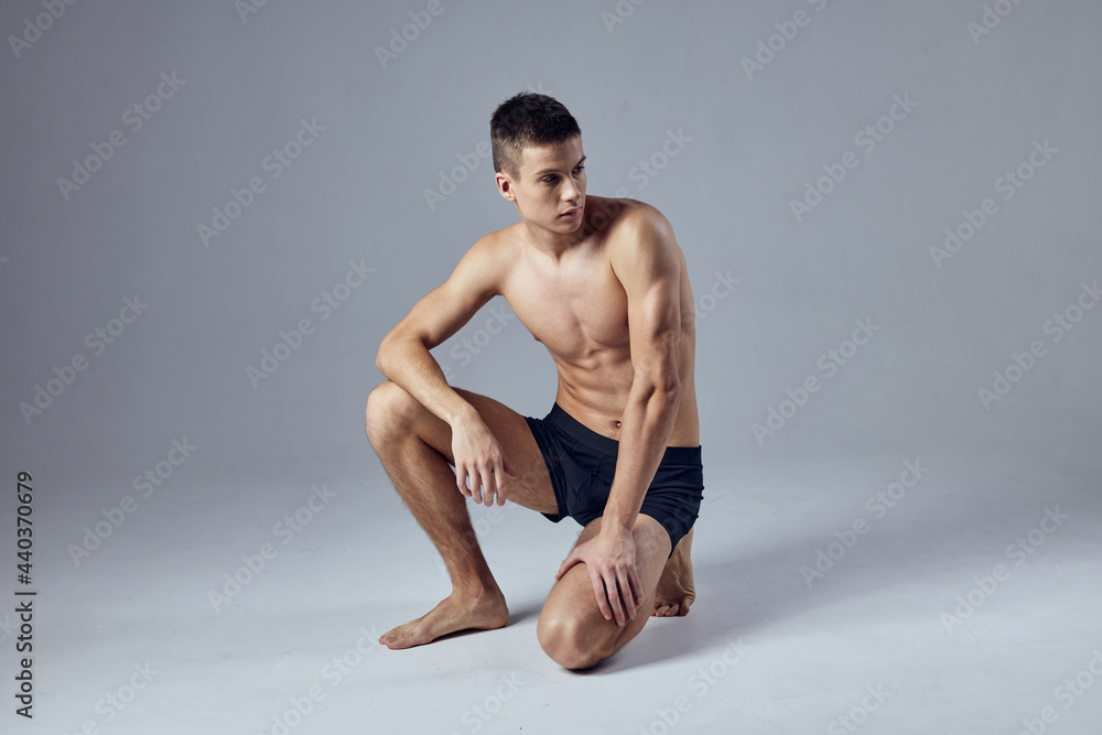 sporty man with muscular body in black shorts isolated background squatting sporty man with muscular body in black shorts isolated background squatting