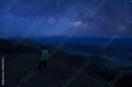 Colorful night sky with stars and silhouette of a standing man on the stone. Blue milky way with man on the mountain. High Rocks. Background with galaxy and silhouette of a man. 