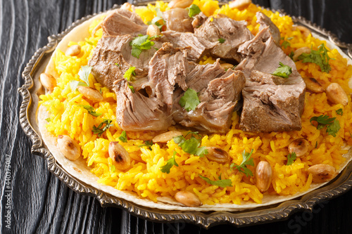 Mansaf is a dish of rice, lamb, and a dry yoghurt made into a sauce called jameed closeup in the plate on the table. horizontal photo