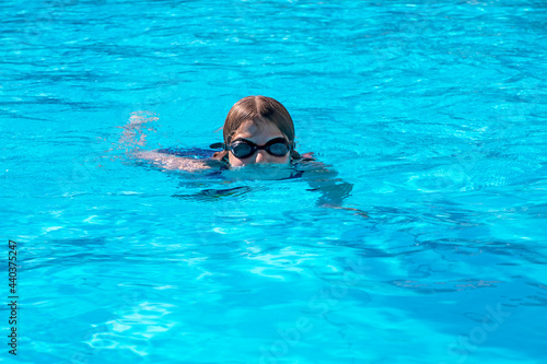 happy girl swims in the pool wearing swimming goggles, horizontal.