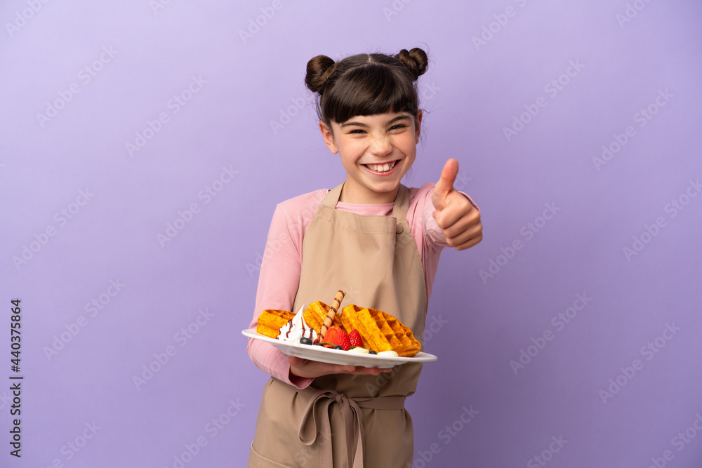 Little caucasian girl holding waffles isolated on purple background with thumbs up because something good has happened Little caucasian girl holding waffles isolated on purple background with thumbs up because something good has happened