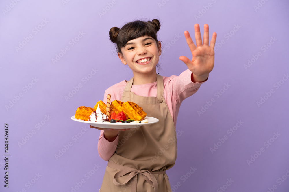 Little caucasian girl holding waffles isolated on purple background counting five with fingers Little caucasian girl holding waffles isolated on purple background counting five with fingers