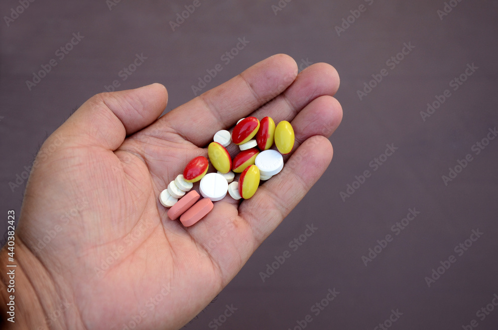 closeup bunch the pink ,white with red,yellow color small medicines tablet, capsule hold hand health care medical concept isolated on purple background. closeup bunch the pink ,white with red,yellow color small medicines tablet, capsule hold hand health care medical concept isolated on purple background.