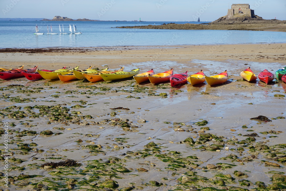 colorful canoes/kayaks moored on the beach at low tide in brittany, france