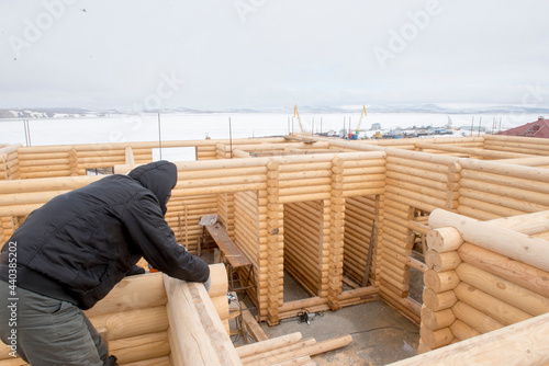 Carpenter works at the construction of wooden house