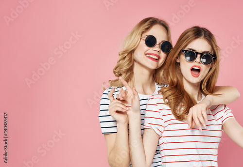 two girlfriends in sunglasses in a striped t-shirt pink background communication © SHOTPRIME STUDIO