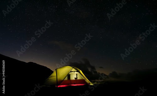 Wild camping tent at night under stary sky in the mountains