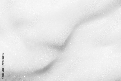White gentle foam texture of modern cleansing cosmetic product for skin care as background extreme close view from above.