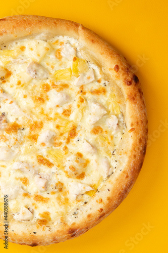 Pizza with cheese and pineapple on a yellow background.