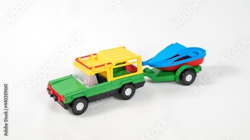 Plastic toy multicolored cars isolated on white background. SUV with a trailer.